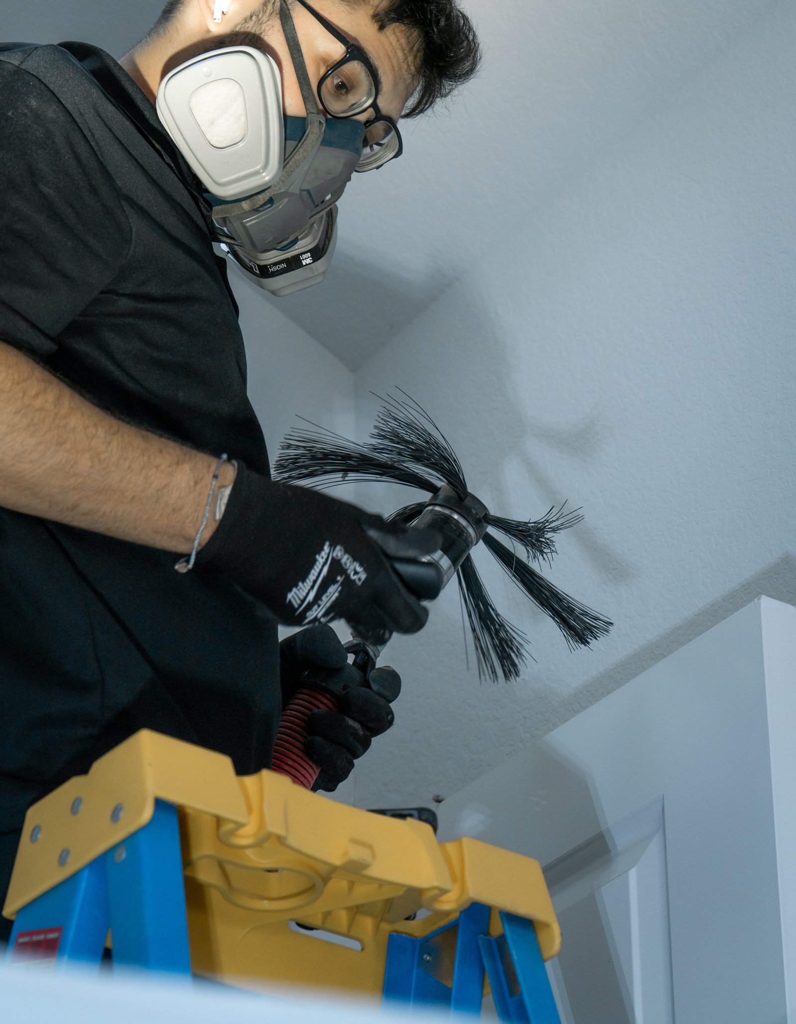 Technician with duct cleaning brush on ladder