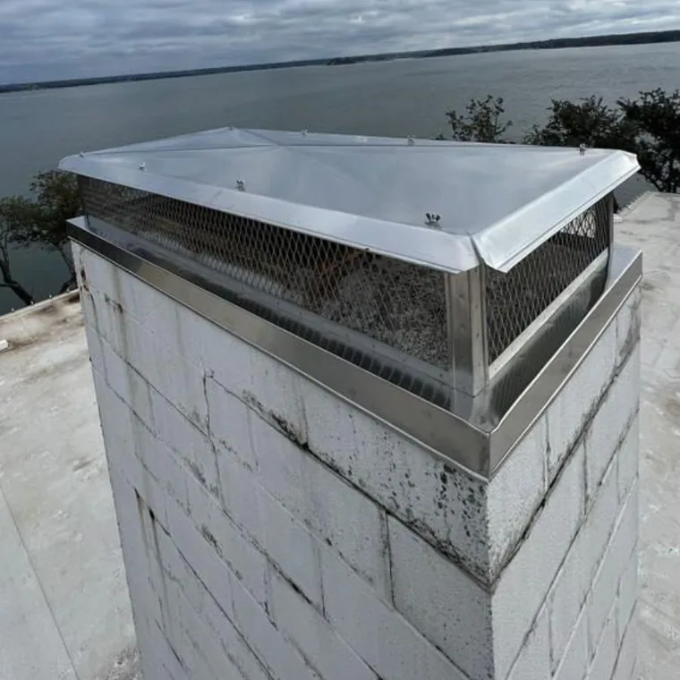 Chimney cap and spark arrestor installed on a lakeside home